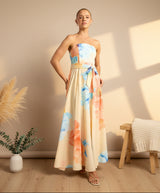 Woman wearing a strapless, long, floral dress on a plain background