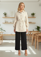 Woman wearing a beige shirt and black pants on a white background